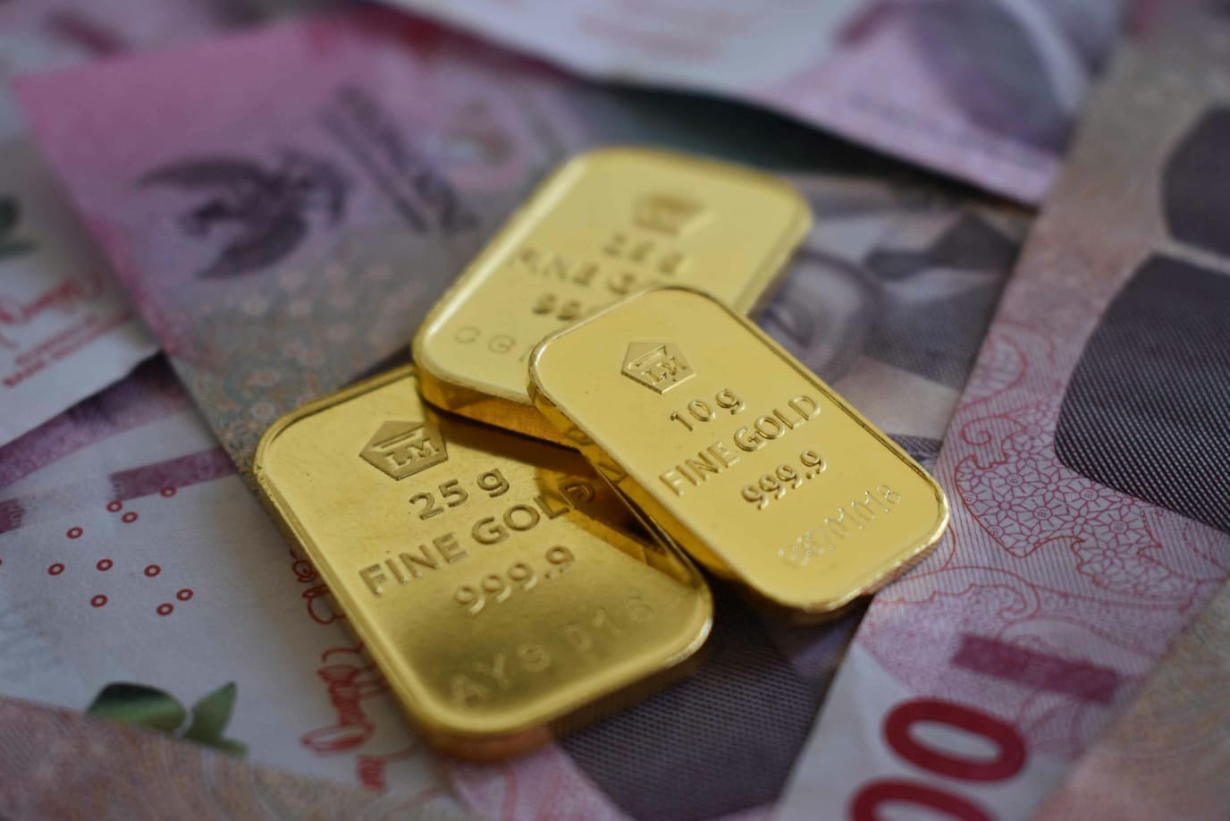 سبائك ذهبية فوق أوراق نقدية تعكس صراع الطلب على الملاذ الآمن مع قوة الدولار